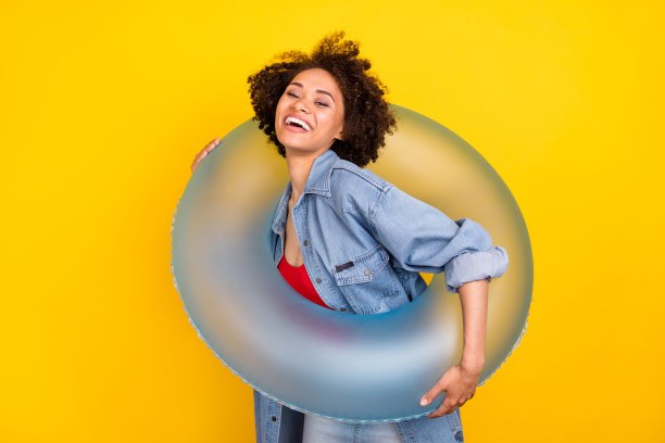 照片：一位快乐的黑皮肤年轻女性，手持水枪，面带微笑，孤立在黄色背景上。图片下载