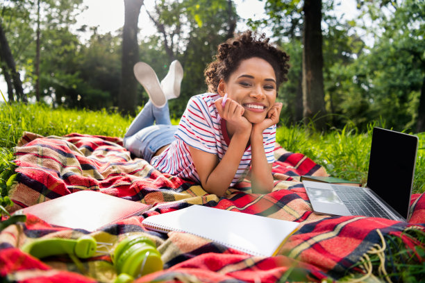 夏季，卷发女孩戴着太阳镜，穿着条纹T恤，在大学校园里行走的照片肖像图片下载