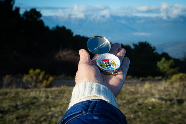 手持打开的指南针，在崎岖的山地景观中导航，在户外探险中寻找方向图片下载