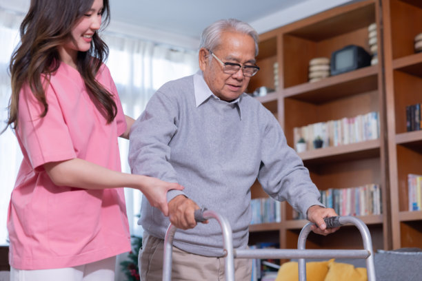 年轻女子在房间里搀扶一位使用助行器的老人图片下载