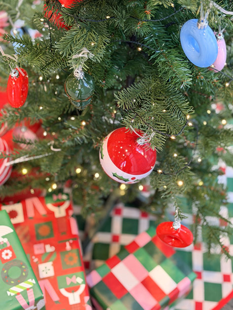 装饰着红色饰球的逼真假针人造云杉圣诞树下堆放着包装好的礼物图片下载