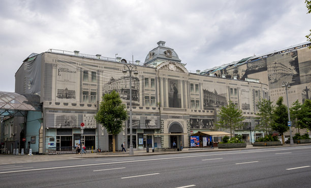 一张经过修复的具有历史意义的剧院建筑，带有复古风格的叠加效果，位于城市街道环境中，周围有树木和公共空间。图片下载