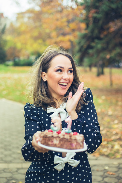 女子在生日蛋糕上吹蜡烛的素材图图片下载