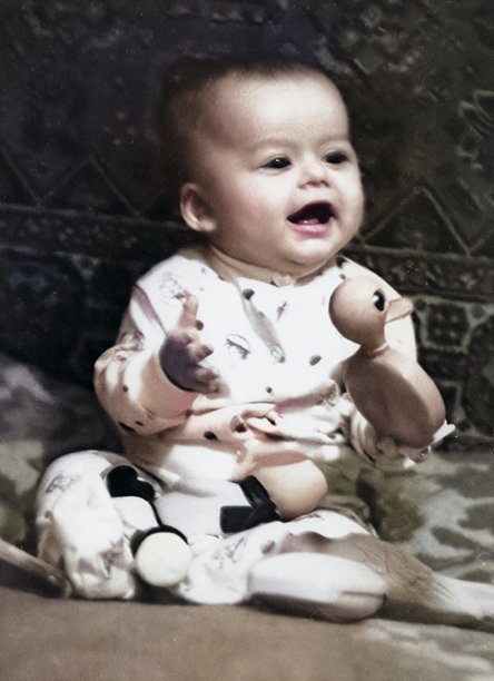 一个甜美微笑的孩子的复古肖像。男孩坐在床上，手里拿着玩具。1968年的复古照片。图片下载