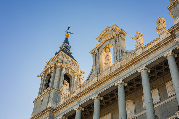 这张图片捕捉了马德里阿尔穆德纳大教堂宏伟的新古典主义外观。其灰白色石材外墙装饰有精美的雕塑、中央钟楼以及朝向王宫的高耸廊柱。图片下载