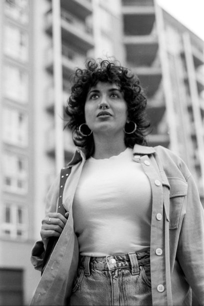 年轻女子在城市背景中抬头仰望，颗粒感的黑白胶片照片图片下载