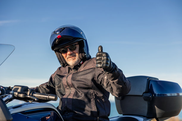 一位年长的男士骑着摩托车，竖起大拇指，展现快乐的生活方式图片下载