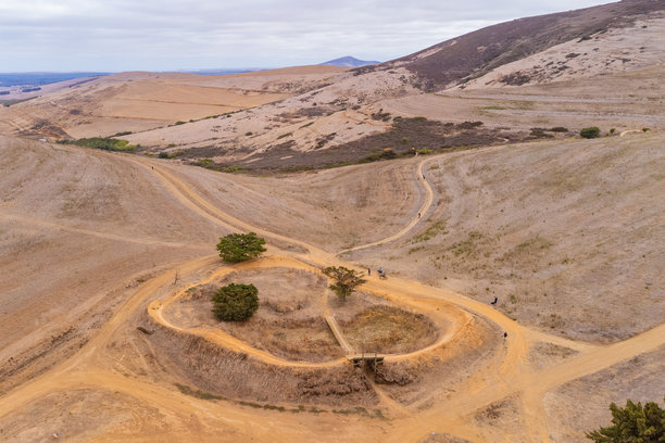 这张图片捕捉了在斯泰伦博斯附近举行的史诗级山地自行车赛的激烈精神，精英骑手们在这里挑战斯泰伦博斯山。一位山地自行车手正在尘土飞扬的单车道上奋力前行，这是西开普省崎岖“未驯服”地形的标志。图片下载
