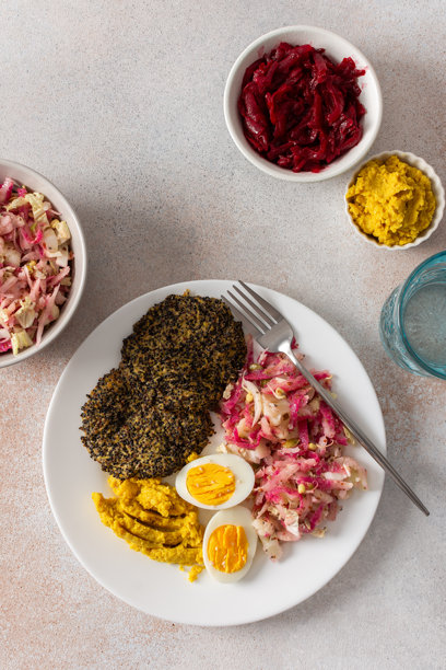 一份营养丰富的早餐，包含藜麦煎饼、新鲜卷心菜、萝卜、绿豆芽、煮鸡蛋、鹰嘴豆泥和烤甜菜，是开启均衡一天的完美选择。图片下载