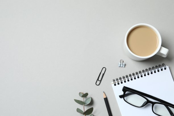 商务概念。工作场所俯视照片，配有计划本、铅笔、眼镜、咖啡杯和桉树，背景为灰色，留有空白空间图片下载