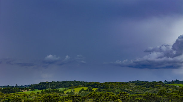 图片展示了郁郁葱葱的绿色山丘和森林景观，背景是戏剧性的图片下载