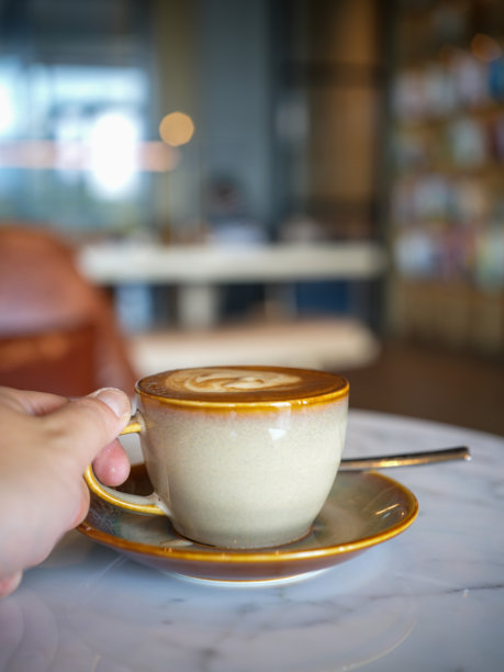 手握着带有拉花艺术的咖啡杯图片下载