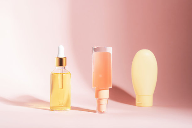 三种化妆品容器，内含精华和液体，摆放在柔软的粉色背景上。正面视图，模型图。图片下载