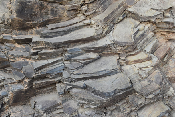 粗糙纹理岩石表面的特写。原始石材表面展现出有机的形状和线条。朴实的岩石纹理，非常适合用作背景或设计素材。图片下载