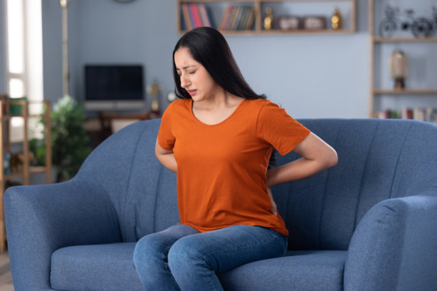 身穿休闲服饰的美丽年轻女孩居家坐在沙发上的照片图片下载