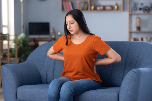 穿着休闲服饰的美丽年轻女孩在家中沙发上坐着的照片图片下载