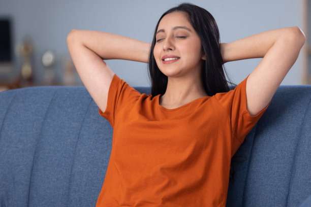 穿着休闲服的美丽年轻女孩在家坐在沙发上的照片素材图片下载