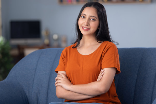 穿着休闲服的年轻漂亮女孩在家坐在沙发上的照片素材图片下载