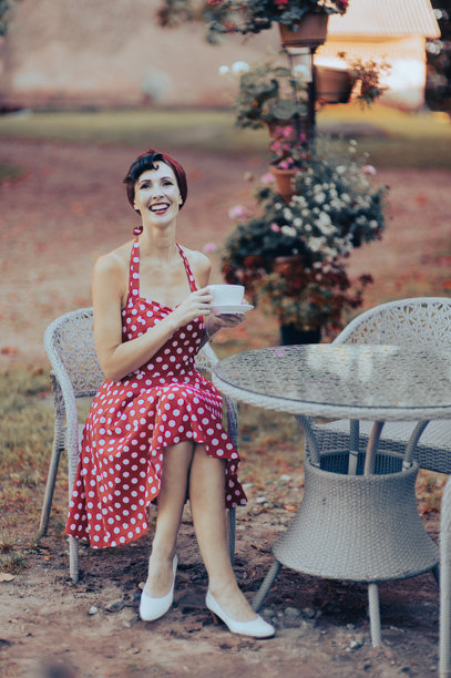一位身穿红裙的美丽女子端着咖啡杯，开怀大笑，复古风格肖像图片下载