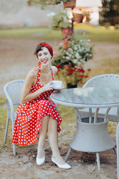 一位身穿红裙的美丽女子手持咖啡杯，开怀大笑，肖像复古风格图片下载