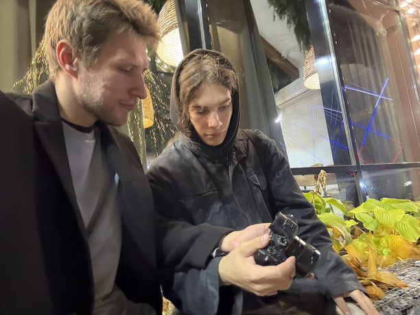 夜幕下的城市里，两个人坐在一起，正在查看相机屏幕上的照片图片下载