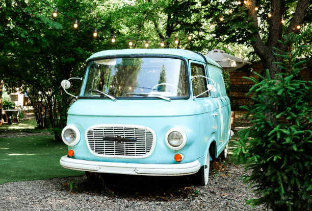 夏天花园里的复古蓝色货车，挂着仙女灯，体现旅行和复古生活方式的素材概念图片下载