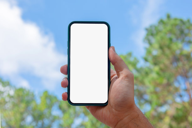 男人在花园里拿着手机，屏幕空白，户外。手机模型。图库照片图片下载