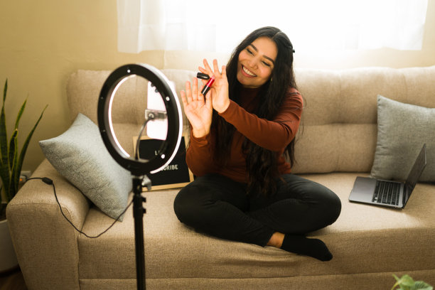 女性视频博主正在为社交媒体录制美妆教程，并在环形灯下展示美妆产品图片下载