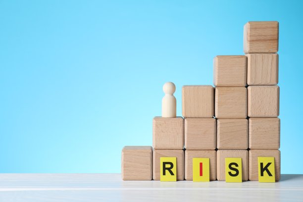 词语“风险”，堆叠的立方体在白色木桌上，背景为浅蓝色，留有文字空间图片下载