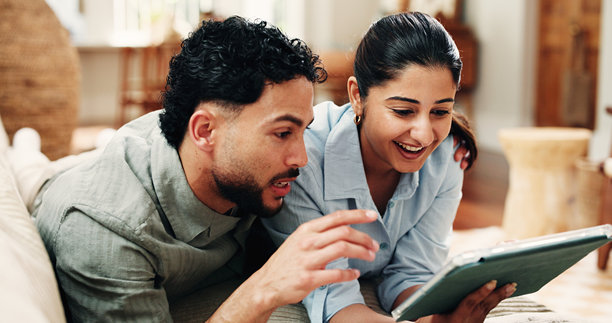 情侣在沙发上依偎着看电影，在订阅网站上搜索或查看新发布的应用。周末在家，快乐的伴侣放松地互相依偎，一起观看流媒体电影或使用科技产品。图片下载