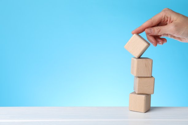 特写：女子在白色木桌前移动立方体，背景为浅蓝色，留有文字空间。图片下载