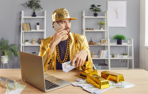 西装革履的有趣男人坐在办公桌前，桌上放着钱，他正用手机打电话。图片下载