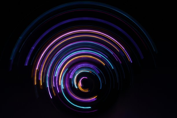 一张长曝光照片。光绘摄影；充满活力的多色仙女灯在黑色背景上形成圆形漩涡图案。图片下载