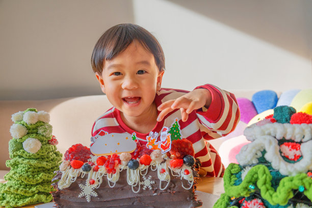 身着圣诞服装的亚洲婴儿，旁边有圣诞蛋糕和许多圣诞装饰。温馨快乐的时光。摄影素材图片下载