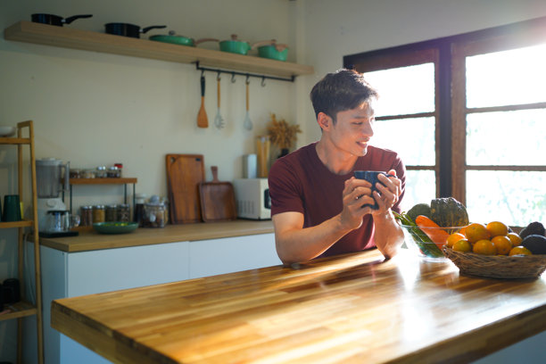 早晨，一位帅气的男人在厨房里喝茶的特写。新的一天。侧面近景照片。空闲时光。早餐概念图片下载