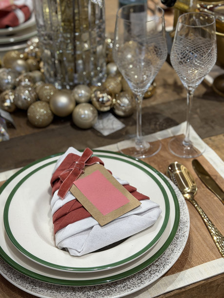 一张优雅的节日餐桌图片，摆放着圣诞树、餐巾、餐具和餐垫，布置精美的餐位。图片下载