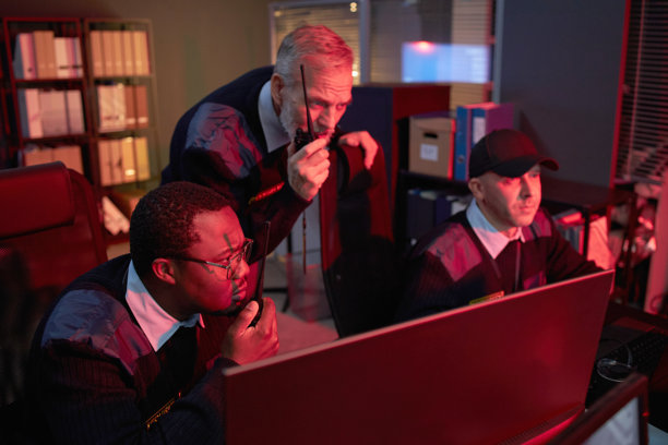 多民族中年保安在夜间监控监控屏幕图片下载