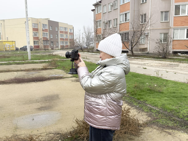 一个人站在户外，手持相机，在街区环境中拍摄照片图片下载