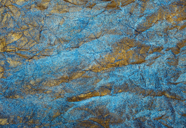 金色和蓝色的抽象背景。一张被涂成金色和蓝色的揉皱纸的照片。图片下载