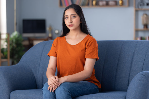 穿着休闲服的美丽年轻女孩在家坐在沙发上的照片图片下载