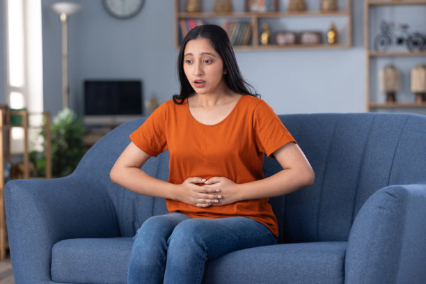 穿着休闲服饰的美丽年轻女孩在家中沙发上坐着的照片图片下载