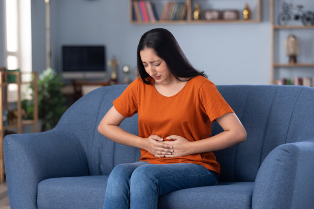 穿着休闲服饰的美丽年轻女孩在家中沙发上坐着的照片图片下载