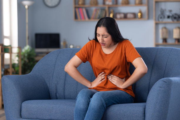 身穿休闲服饰的漂亮年轻女孩在家中沙发上坐着的照片图片下载
