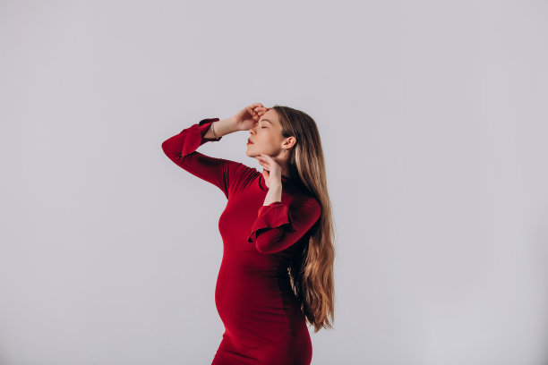 年轻美丽的孕妇模特，长发，身穿华丽红裙，在影棚内图片下载