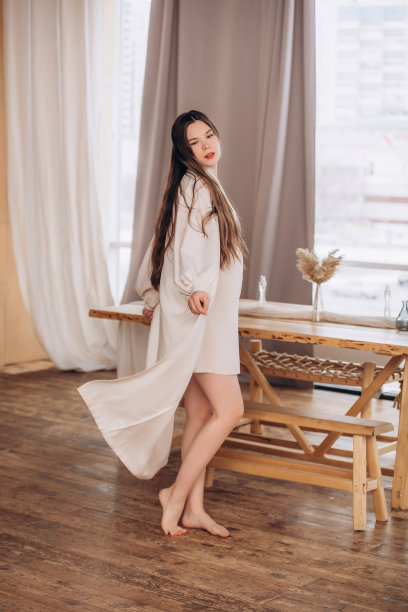 年轻美丽的孕妇模特，留着长发，身穿漂亮的米色连衣裙，在家中图片下载