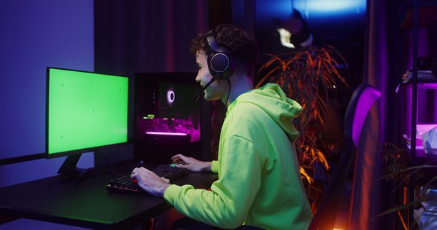 一名少年坐在电脑前玩游戏。图片下载