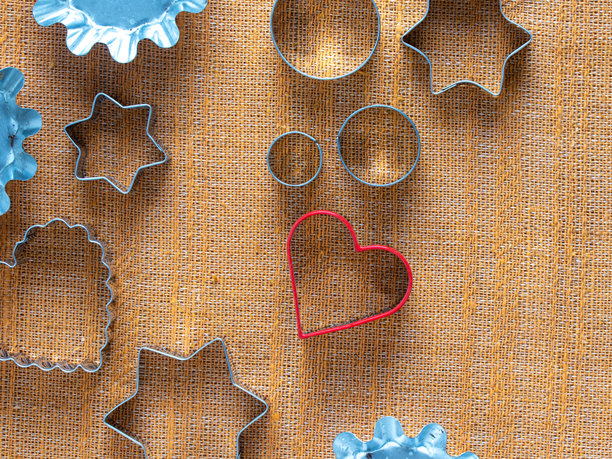 各种金属饼干模具，包括圆形、星形、扇形和红心形，放置在有纹理的表面上。适用于烘焙饼干、翻糖或橡皮泥。图片下载