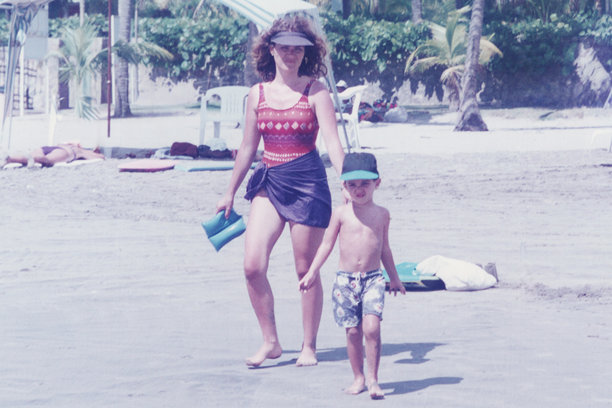 20世纪80年代在海滩拍摄的照片：一位年轻的女大学生微笑着看向镜头，身穿泳衣摆拍。图片下载