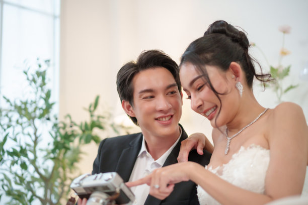 亚洲新婚夫妇微笑着查看相机照片图片下载