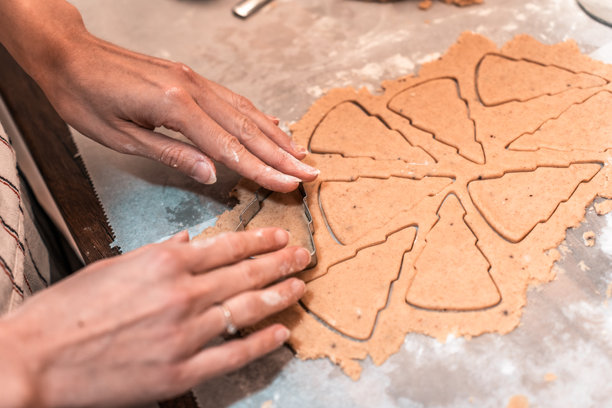 烘焙圣诞树饼干：用饼干模具切割面团，制作节日美食和季节性庆典的家庭烘焙图片下载